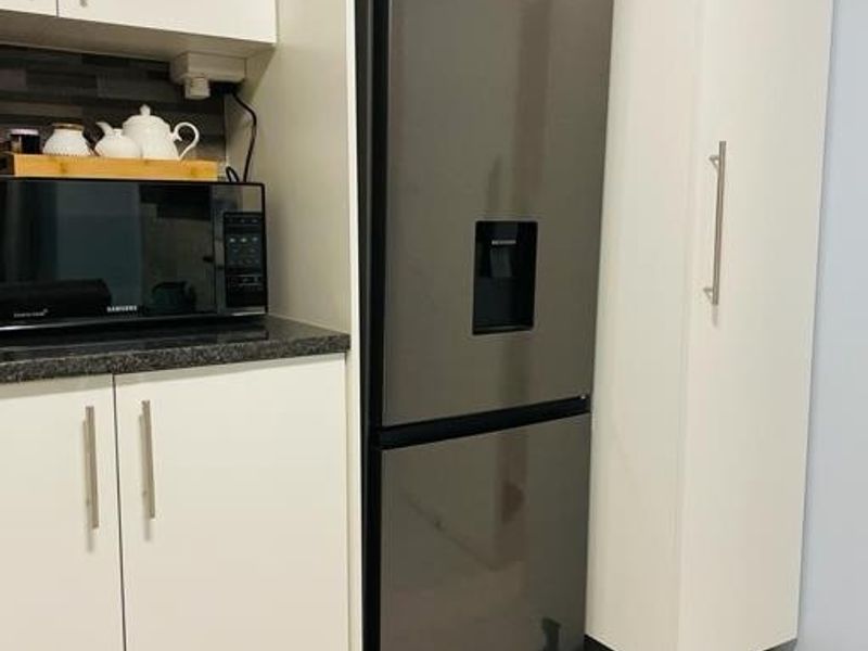 A modern kitchen area featuring white cabinetry, dark countertops, and tiled flooring, providing a clean and functional space.