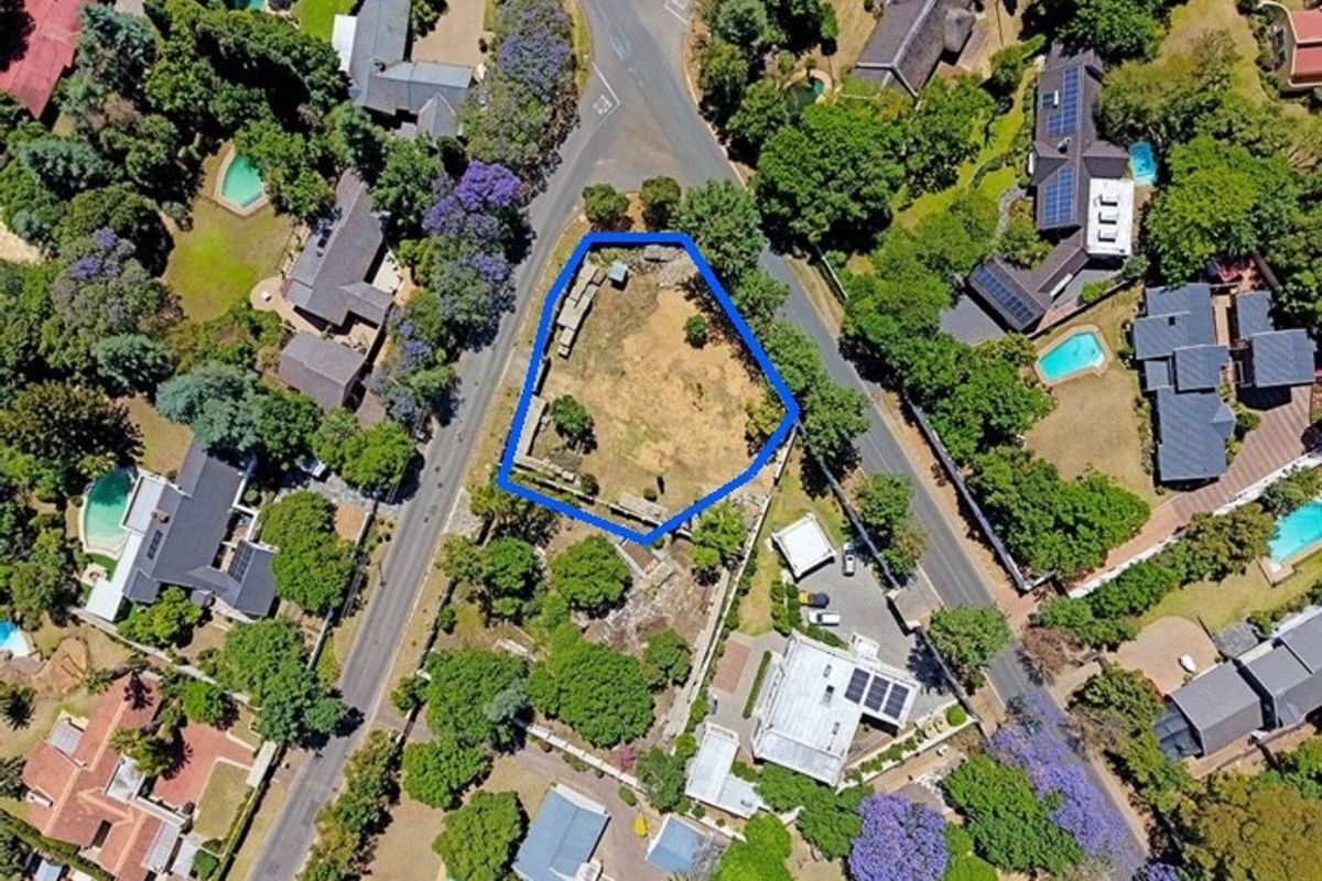 Aerial view of a vacant residential plot highlighted in blue, situated within an established suburban neighborhood with mature trees and surrounding properties.