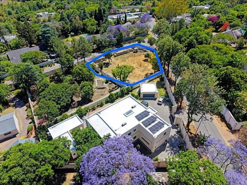 Aerial view of a vacant residential land plot highlighted in blue, situated within a well-established, tree-lined suburban neighborhood.