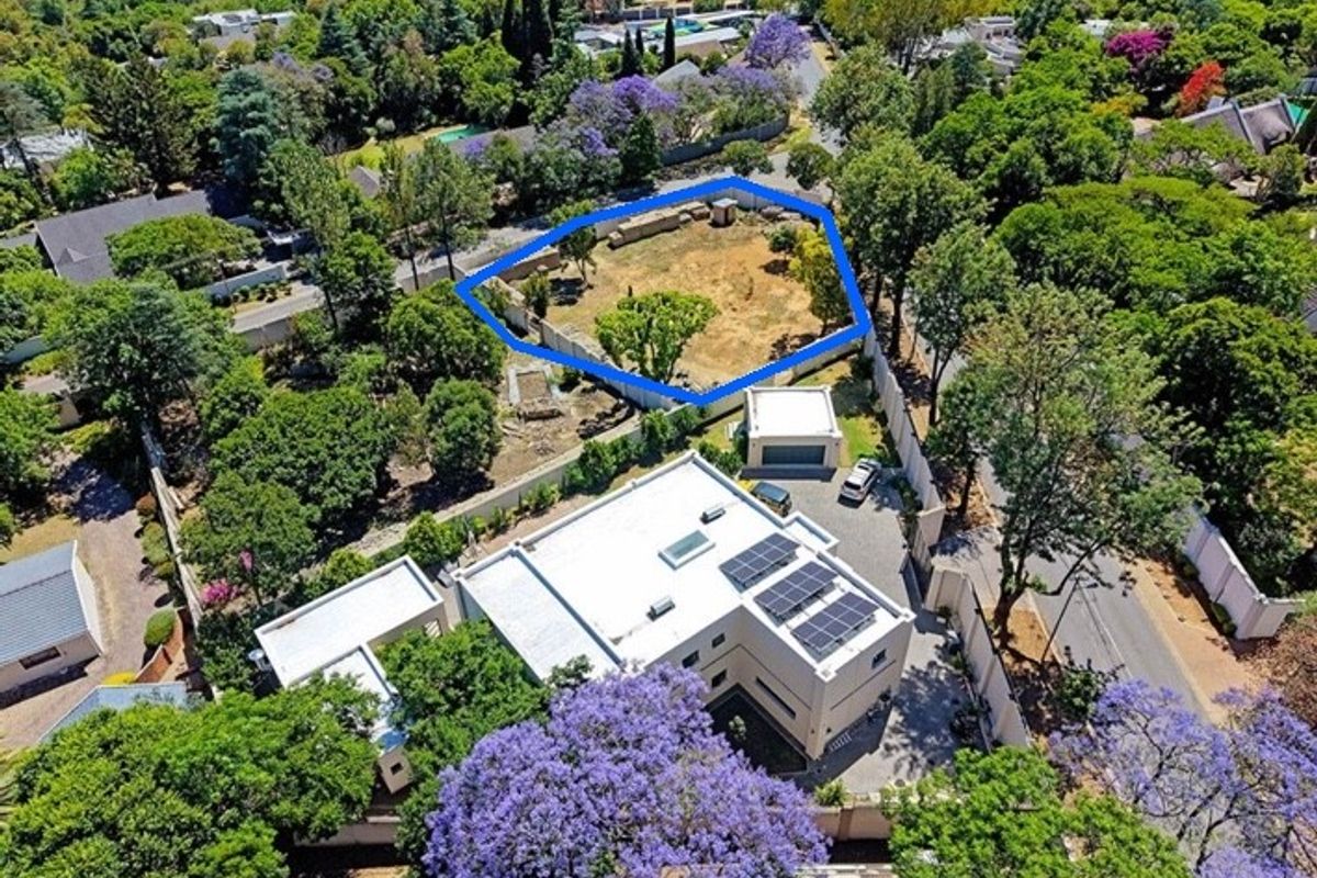 Aerial view of a vacant residential land plot highlighted in blue, situated within a well-established, tree-lined suburban neighborhood.