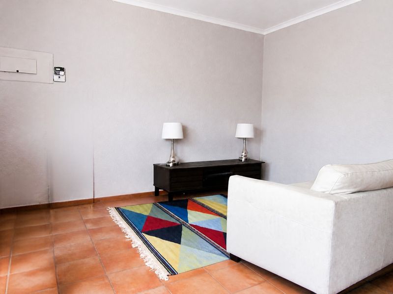 A living room area featuring terracotta floor tiles, a neutral wall finish, and integrated electrical and intercom infrastructure.