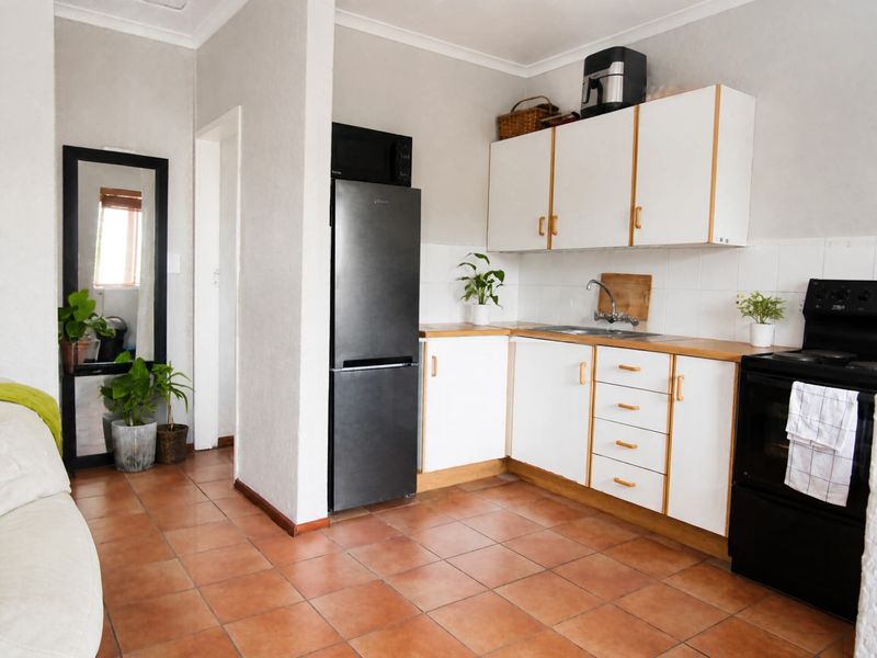 A functional kitchen featuring white cabinetry, wood-look countertops, tiled flooring, and a tiled backsplash, providing a clean and practical cooking space.
