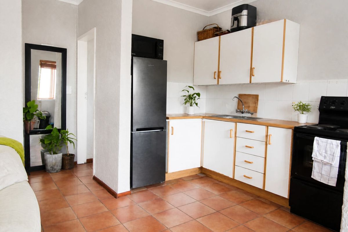 A functional kitchen featuring white cabinetry, wood-look countertops, tiled flooring, and a tiled backsplash, providing a clean and practical cooking space.