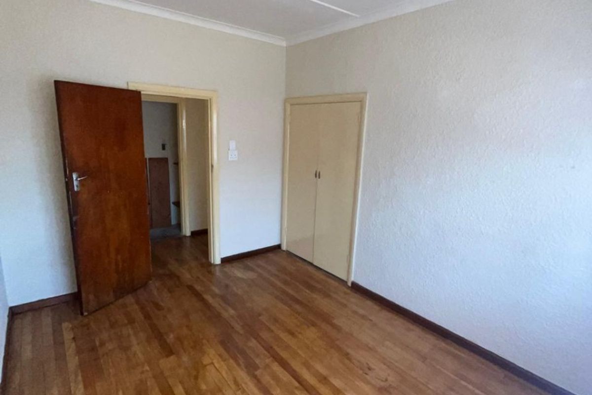 A vacant bedroom featuring original hardwood flooring, built-in storage cupboards, and neutral wall finishes, offering a blank canvas for personalization.