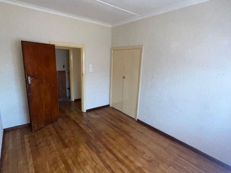 A vacant bedroom featuring original hardwood flooring, built-in storage cupboards, and neutral wall finishes, offering a blank canvas for personalization.