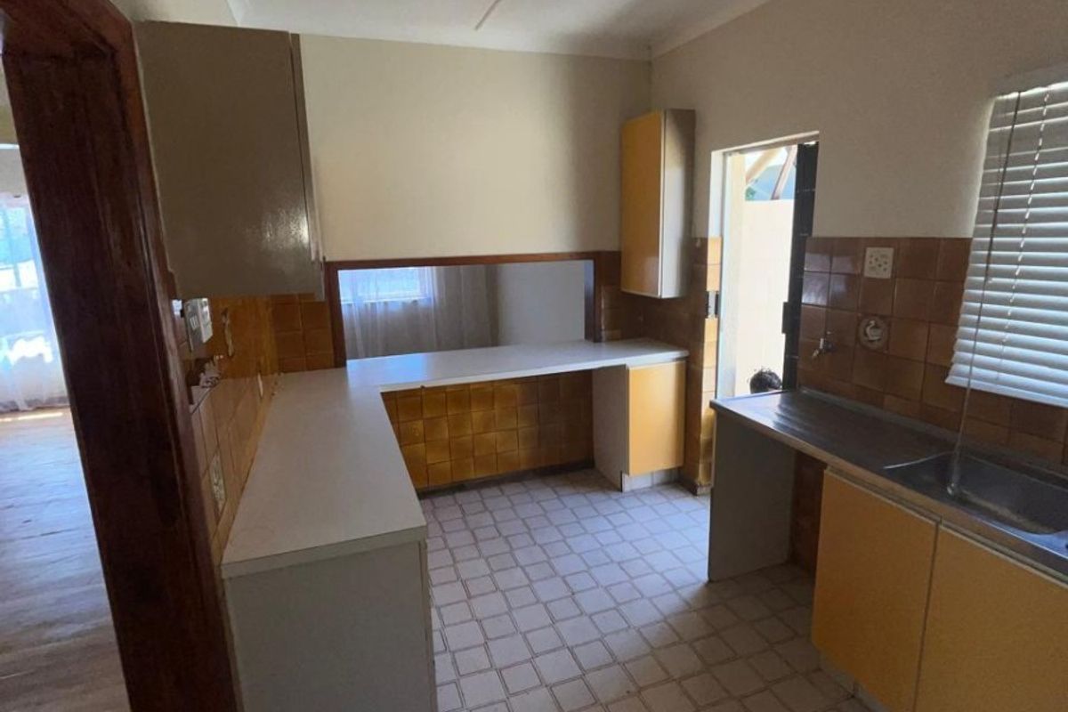 A functional, dated kitchen featuring original cabinetry, tiled backsplash, and tiled flooring, offering a blank canvas for modern renovation and design updates.