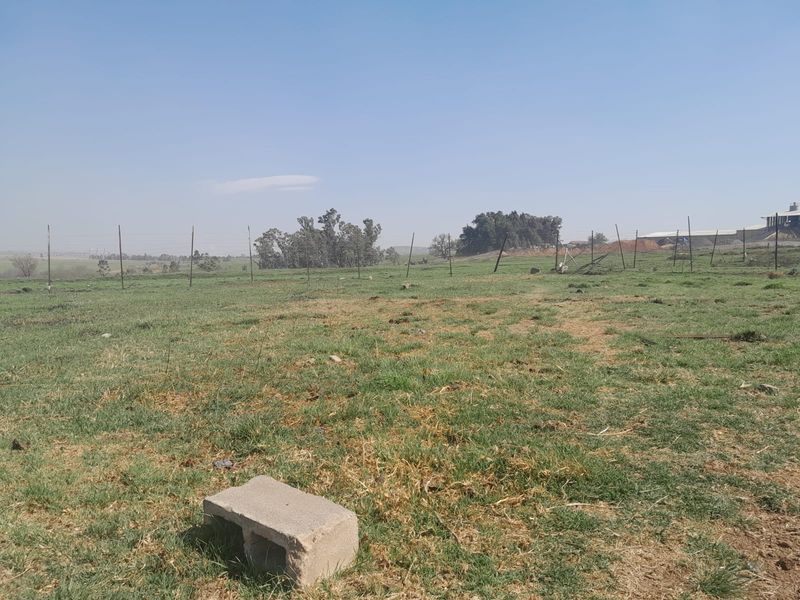 Expansive open farm land featuring natural pasture and perimeter wire fencing under a clear sky.