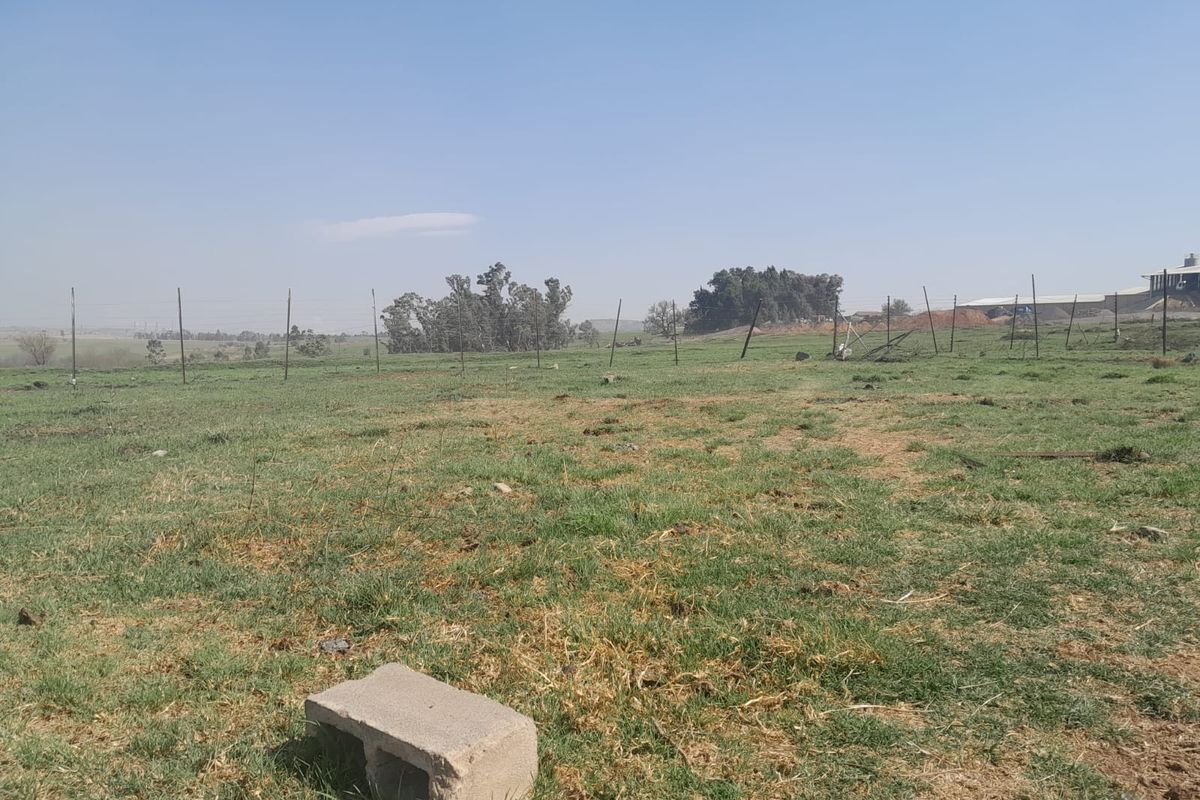 Expansive open farm land featuring natural pasture and perimeter wire fencing under a clear sky.