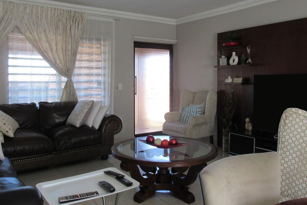 A comfortable living room featuring tiled flooring, decorative cornicing, and a built-in wall shelving unit for media storage.