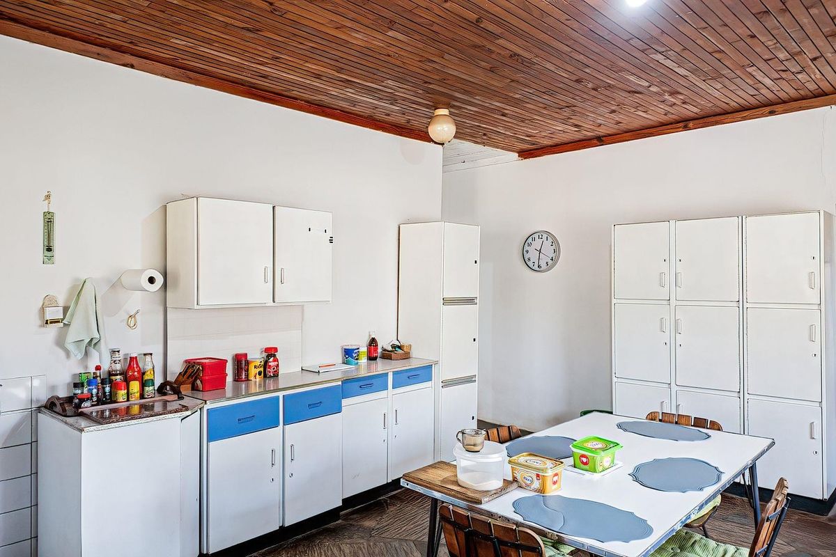 A functional kitchen featuring dated white and blue cabinetry, laminate countertops, and a traditional timber tongue and groove ceiling.
