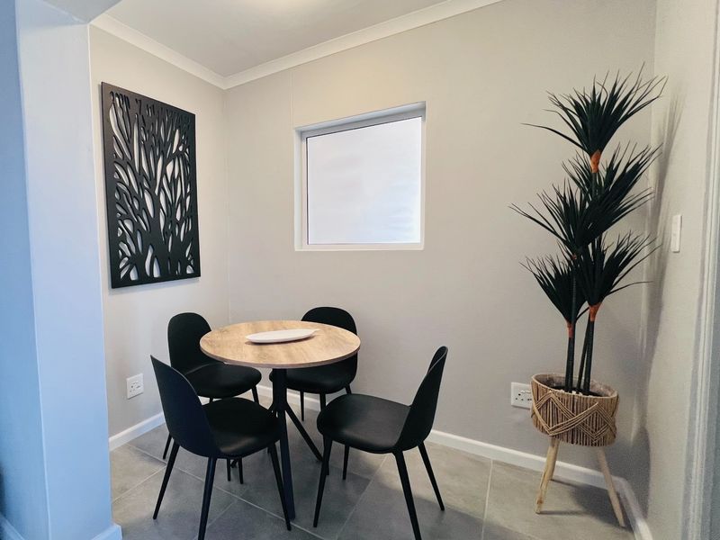 A compact dining area featuring neutral wall tones, tiled flooring, and a small window, providing a clean and functional space for casual meals.