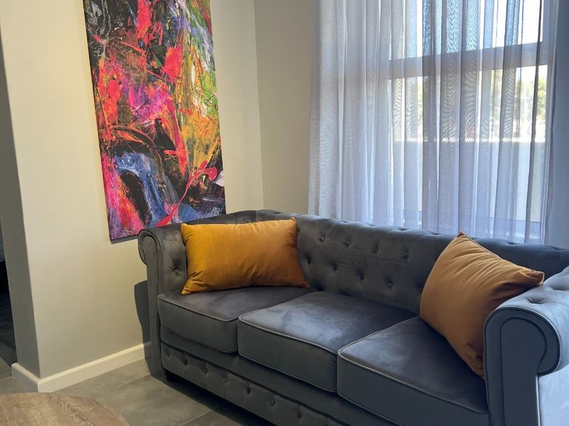 A well-maintained living area featuring neutral tiled flooring and a large window with fitted curtain hardware.