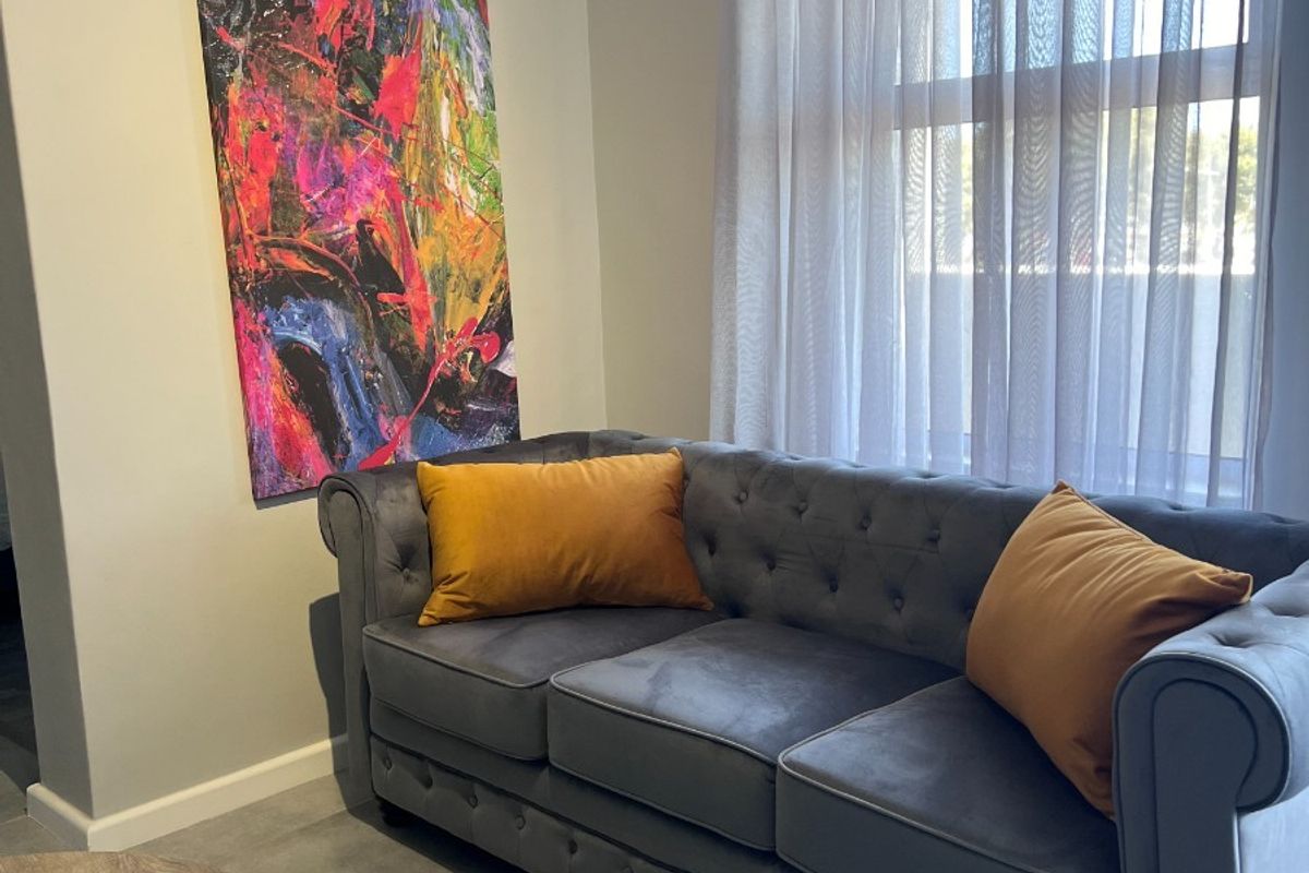 A well-maintained living area featuring neutral tiled flooring and a large window with fitted curtain hardware.