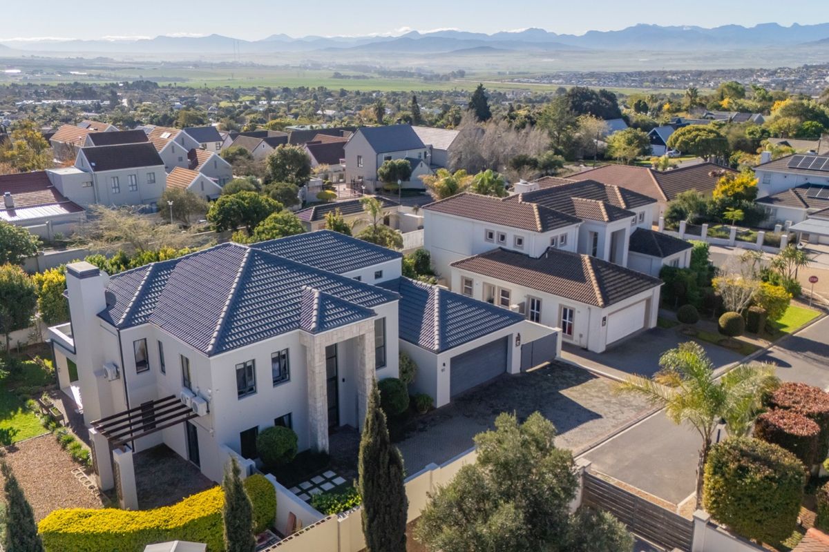 Aerial view of a modern residential property featuring a tiled roof, paved driveway, and well-maintained garden within a suburban estate setting.
