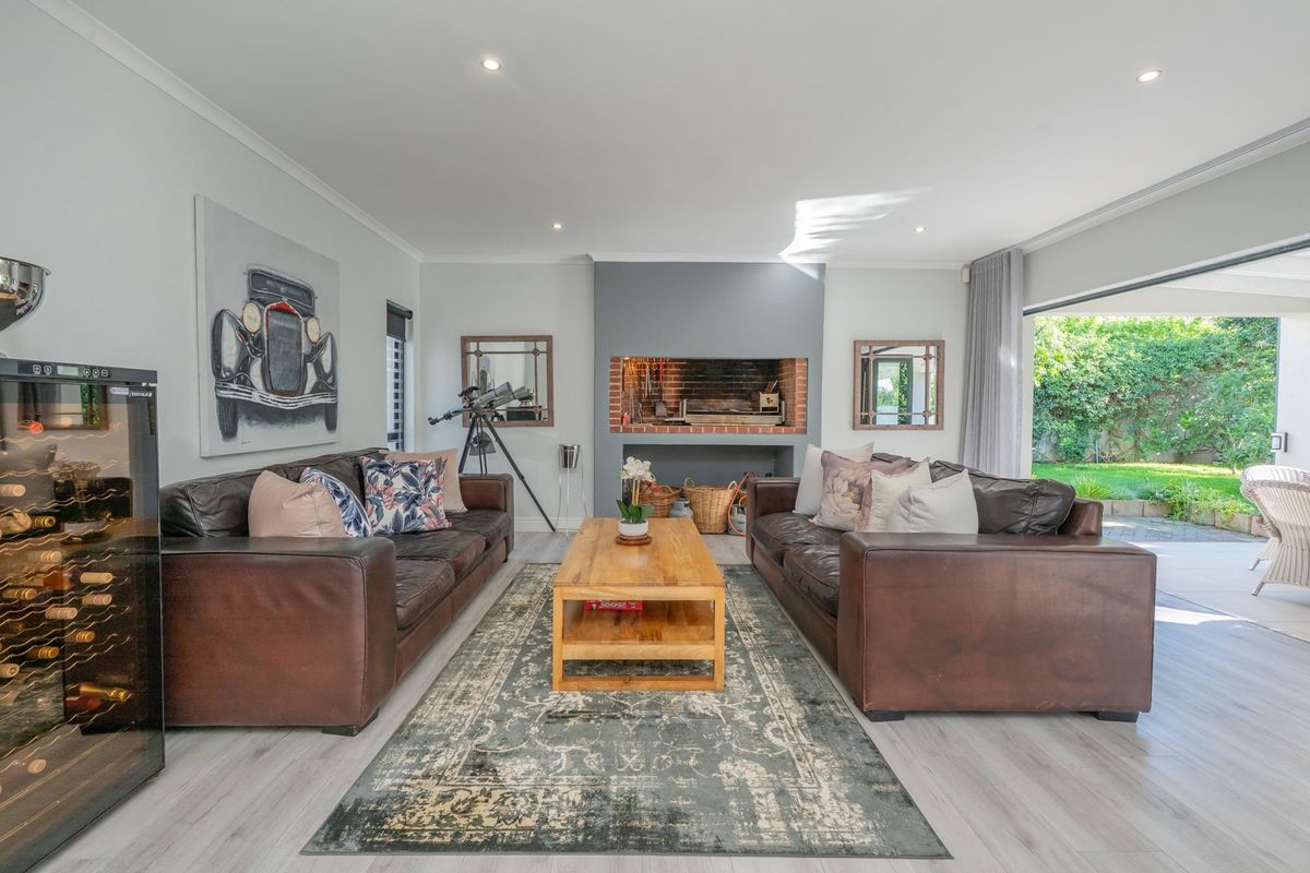 Spacious living room featuring a built-in indoor braai, modern laminate flooring, and large sliding doors providing seamless access to the outdoor patio area.