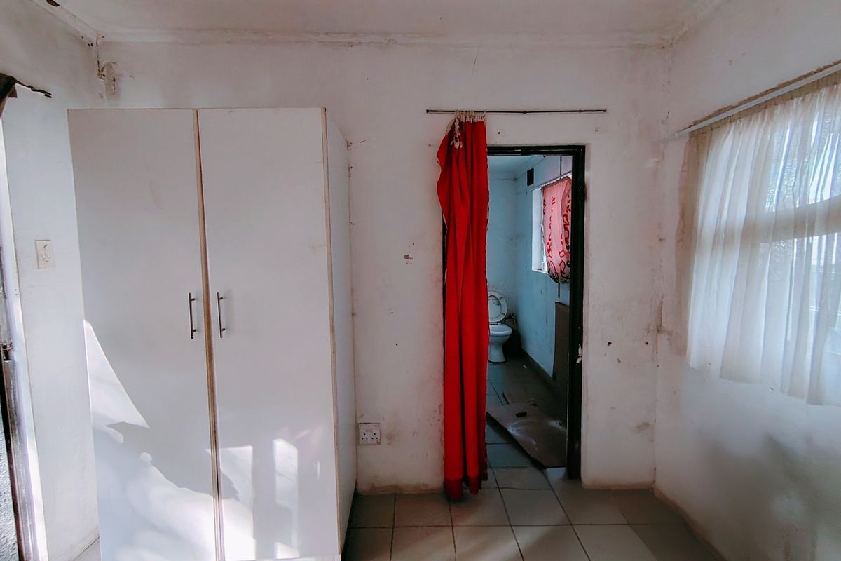 A bedroom featuring tiled flooring and a built-in wardrobe, with an adjoining bathroom visible through the doorway.