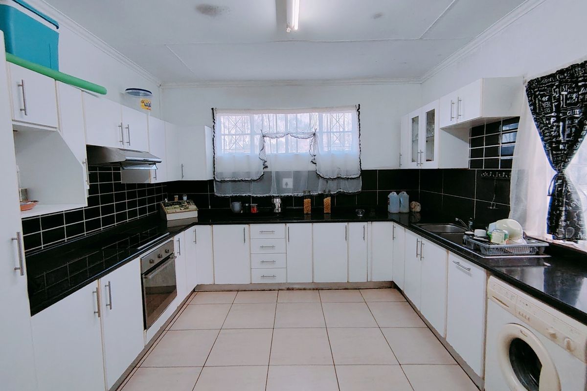 A functional U-shaped kitchen featuring white cabinetry, black tiled backsplash, dark granite countertops, and integrated stainless steel appliances.