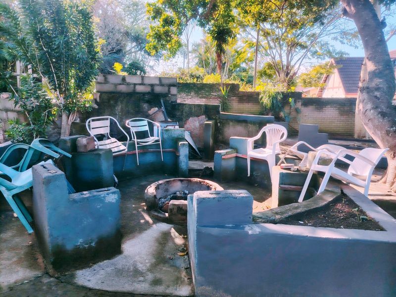 Outdoor entertainment area featuring a built-in fire pit and masonry seating, set within a private garden space with brick boundary walls.