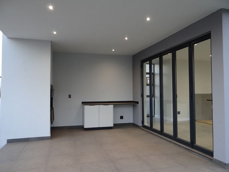 Covered patio featuring tiled flooring, built-in cabinetry with countertop, recessed lighting, and large stacking glass doors providing seamless indoor-outdoor flow.