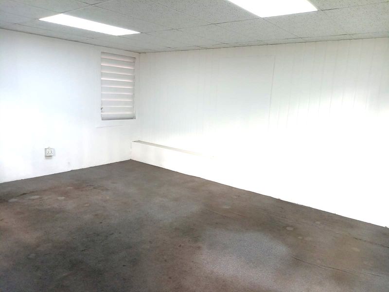 An empty office space featuring a suspended ceiling, recessed lighting, and a window with fitted blinds, ready for custom fit-out.