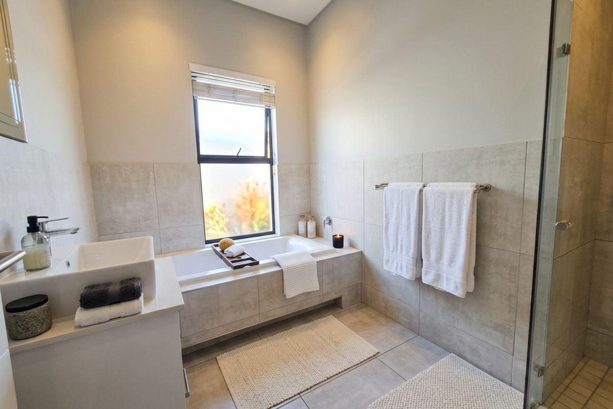 Modern bathroom featuring a built-in bathtub, separate glass-enclosed shower, and contemporary vanity basin with neutral wall and floor tiling.