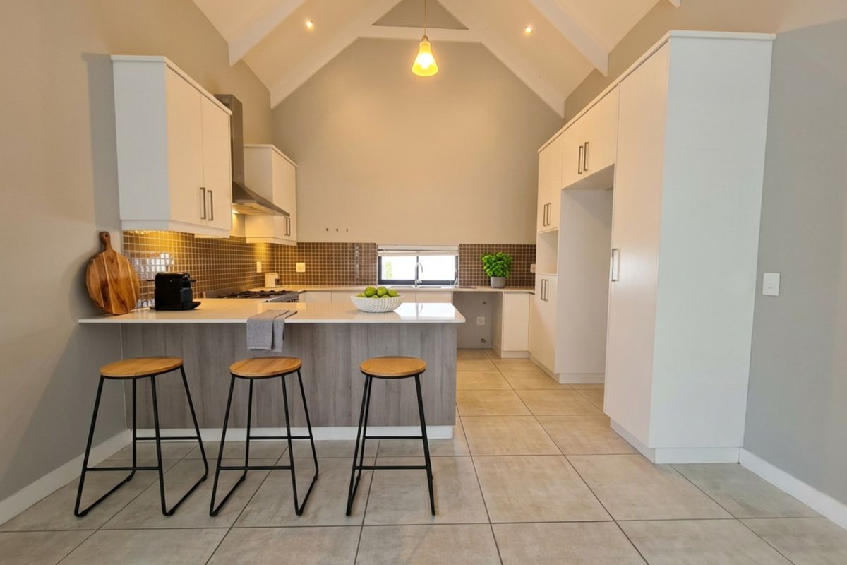 Modern kitchen featuring a high vaulted ceiling, stone countertops, breakfast bar, tiled backsplash, and ample built-in cabinetry with integrated appliances.