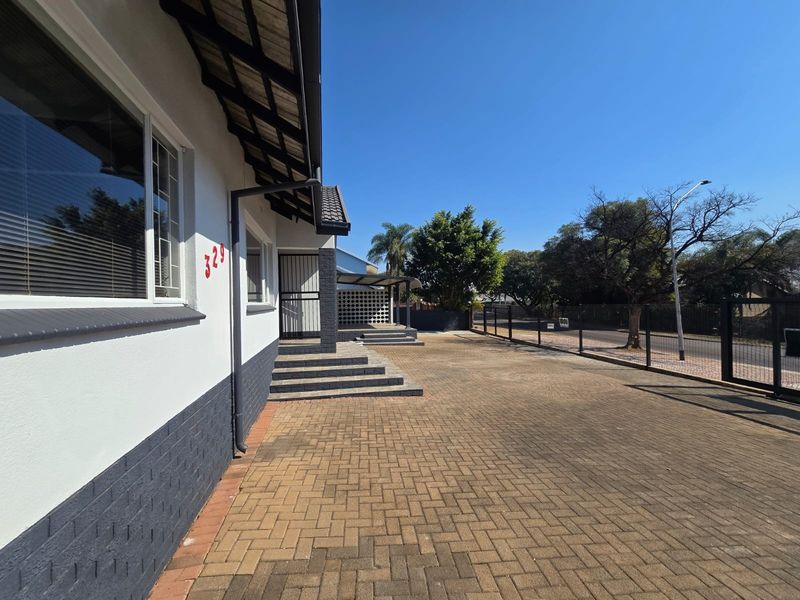 A well-maintained front exterior view featuring a paved driveway, secure perimeter fencing, and a clean, modern facade with a tiled roof.