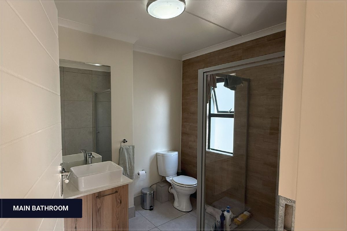 A modern bathroom featuring a vessel sink vanity, a toilet, and a glass-enclosed shower with wood-look wall tiling.