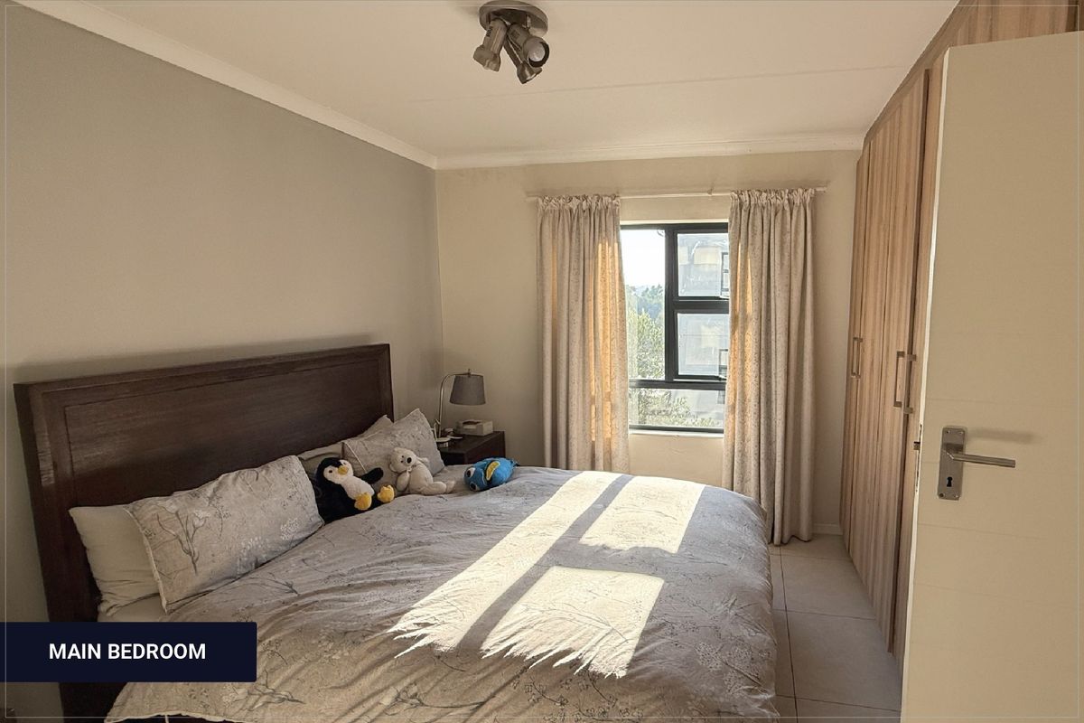 A well-lit bedroom featuring built-in wooden cupboards, tiled flooring, and a window allowing natural light to brighten the space.