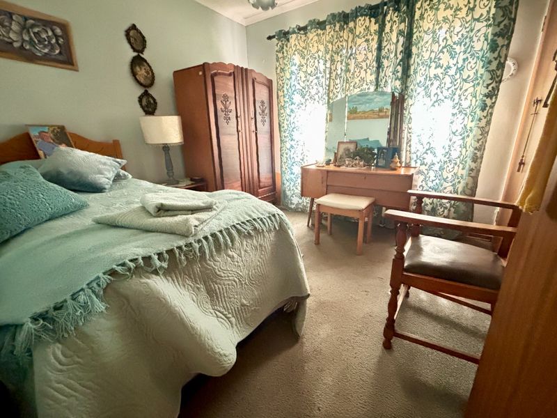 A bedroom featuring carpeted flooring and window treatments, offering a functional space with potential for modernization.