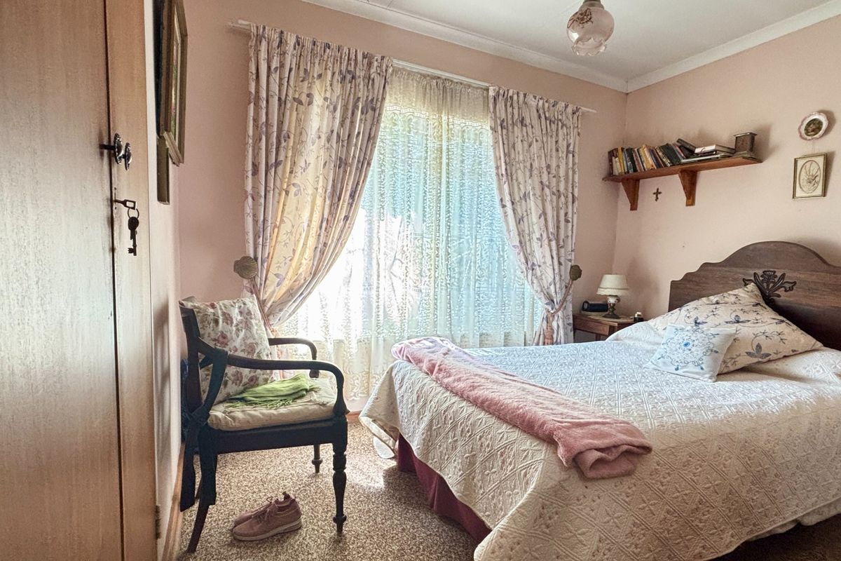 A cozy bedroom featuring carpeted flooring, a built-in wardrobe, and a window with natural light.