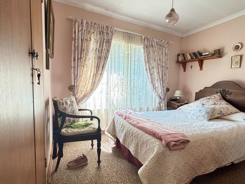 A cozy bedroom featuring carpeted flooring, a built-in wardrobe, and a window with natural light.