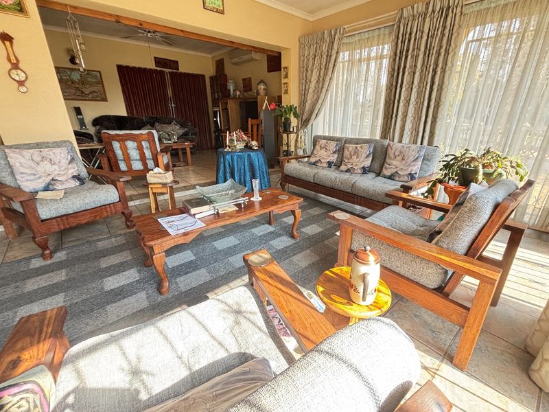Spacious living area featuring tiled flooring, ceiling fan, air conditioning, and large sliding glass doors providing ample natural light.