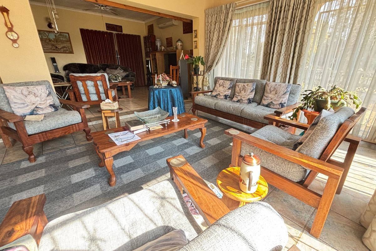 Spacious living area featuring tiled flooring, ceiling fan, air conditioning, and large sliding glass doors providing ample natural light.