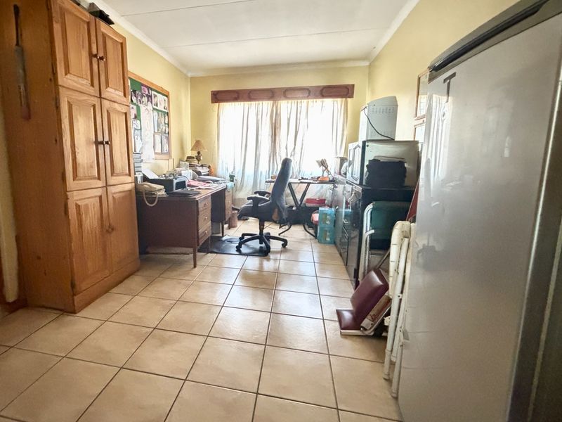 A functional office space featuring tiled flooring and a built-in wooden cupboard, offering a practical layout for a home workspace.