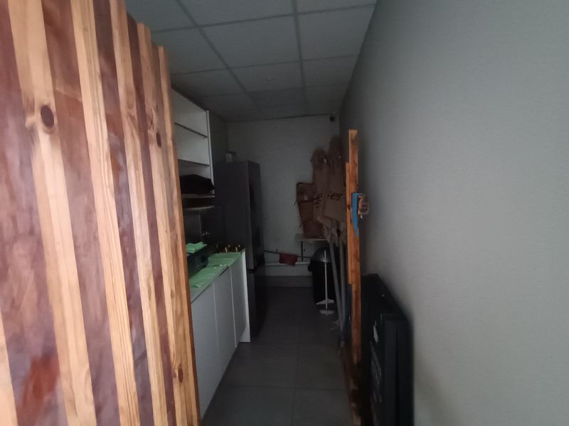 A narrow utility or scullery area featuring built-in cabinetry, tiled flooring, and a drop ceiling, suitable for storage or food preparation.