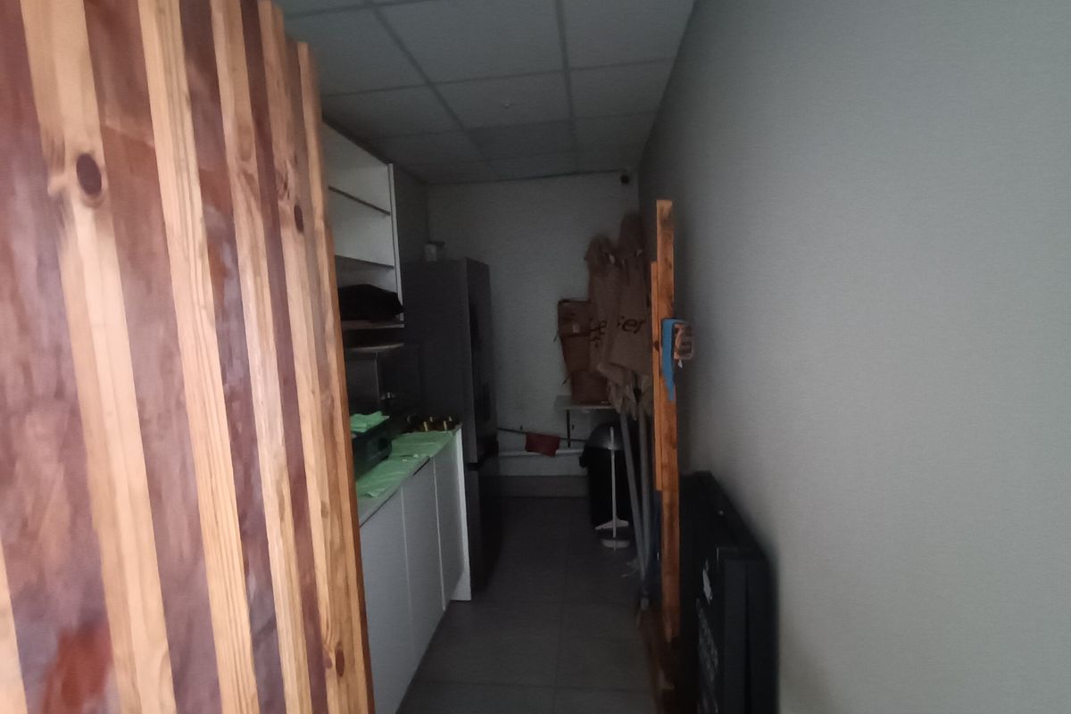 A narrow utility or scullery area featuring built-in cabinetry, tiled flooring, and a drop ceiling, suitable for storage or food preparation.