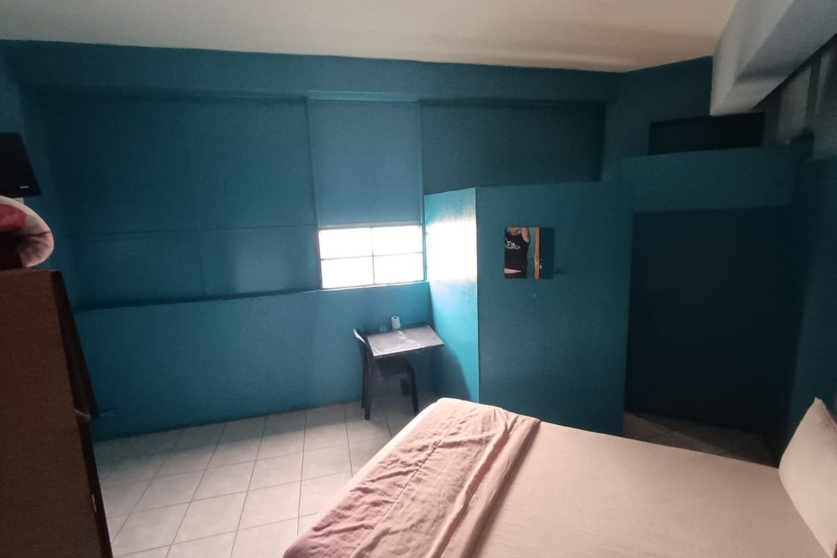 A bedroom space featuring tiled flooring and a partition wall, currently finished in a bold blue paint.