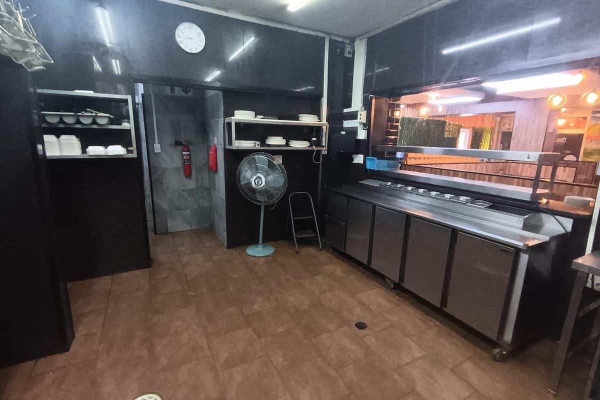 Commercial kitchen area featuring stainless steel prep counters, built-in shelving, and functional utility fixtures, suitable for food service operations.