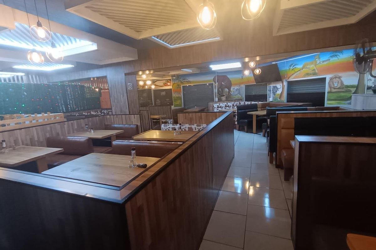 Commercial dining area featuring built-in booth seating, tiled flooring, and decorative ceiling panels with integrated lighting.