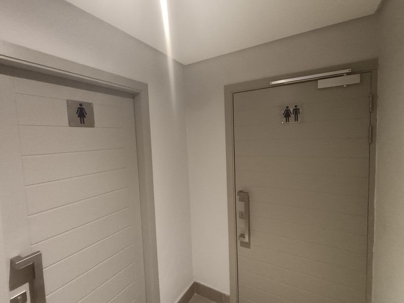 A clean hallway featuring two modern doors with signage leading to separate restroom facilities.