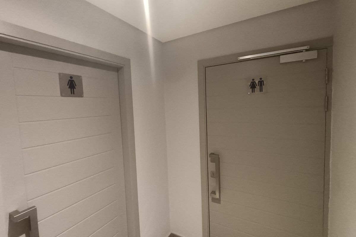 A clean hallway featuring two modern doors with signage leading to separate restroom facilities.