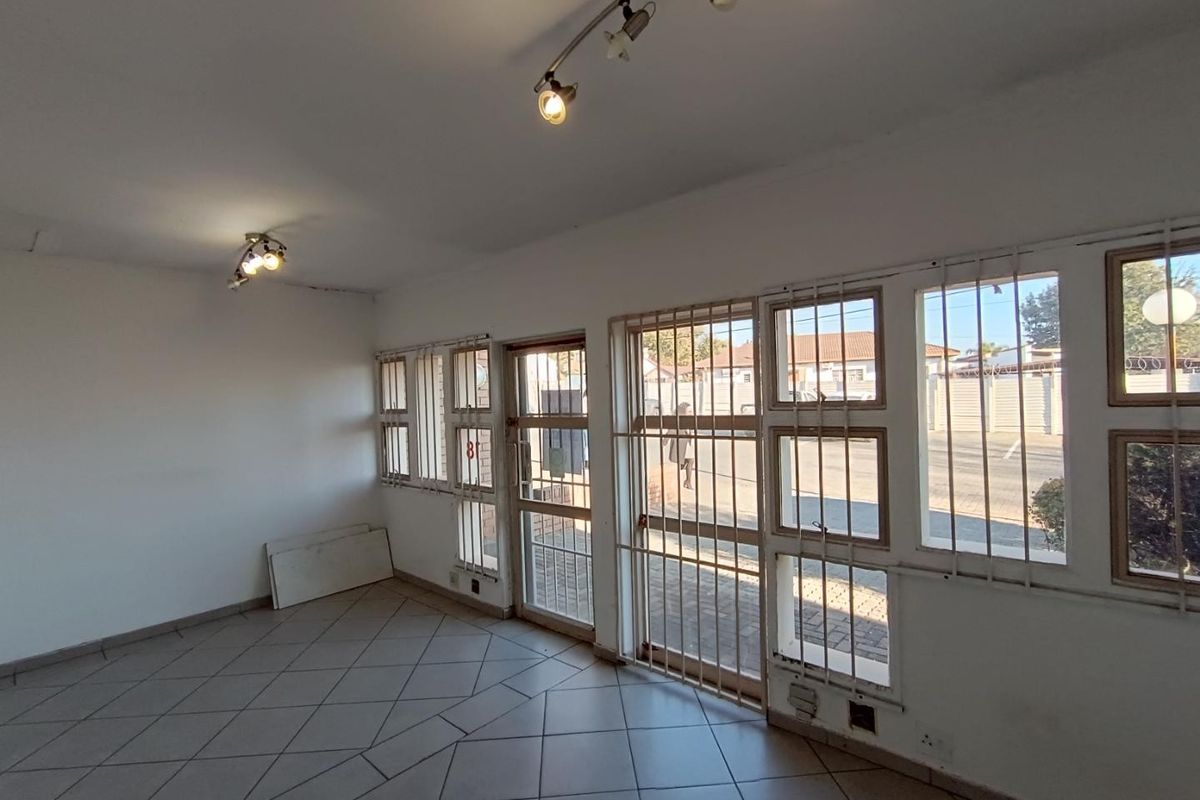 An empty commercial space featuring ceramic tiled flooring, track lighting, and large windows with security bars, offering a blank canvas for business customization.