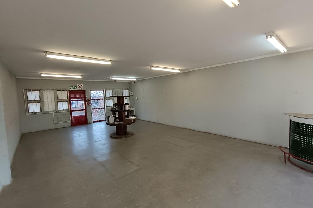 Spacious open-plan commercial area featuring concrete flooring, fluorescent lighting, and secure access points, suitable for a variety of retail or office configurations.
