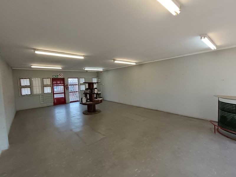 Spacious open-plan commercial area featuring concrete flooring, fluorescent lighting, and secure access points, suitable for a variety of retail or office configurations.