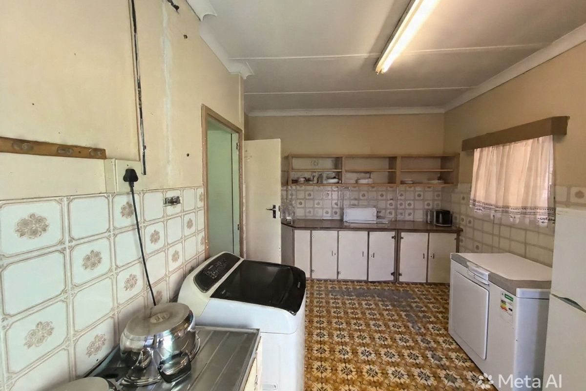 A dated kitchen featuring original patterned floor tiles, tiled backsplash, and built-in cabinetry, requiring significant renovation and cosmetic updates.