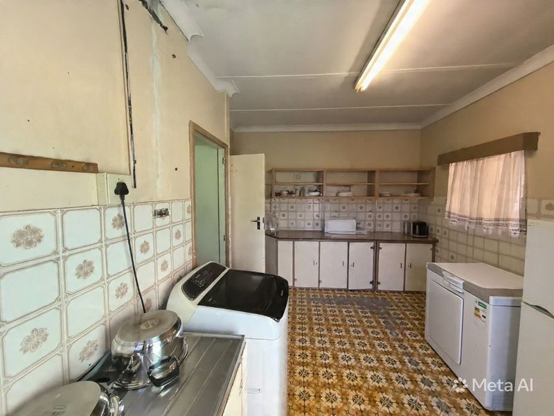 A dated kitchen featuring original patterned floor tiles, tiled backsplash, and built-in cabinetry, requiring significant renovation and cosmetic updates.
