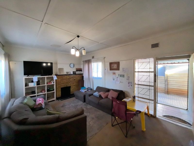 Living room featuring a brick fireplace, ceiling tiles, and direct access to an outdoor area through a security gate.