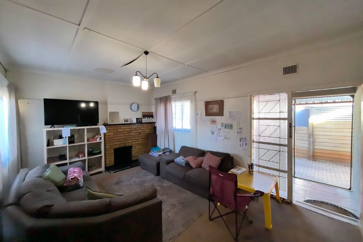 Living room featuring a brick fireplace, ceiling tiles, and direct access to an outdoor area through a security gate.