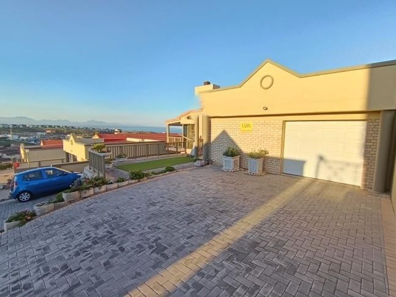 Front exterior view of the property featuring a paved driveway, single garage, and elevated terrace area with coastal views.